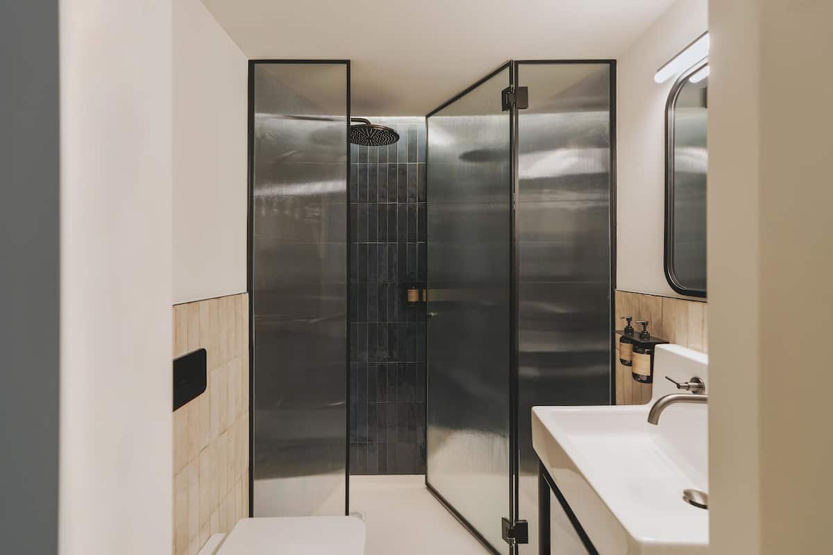 A modern bathroom with a glass-enclosed shower, a white sink, and a mirror above it.