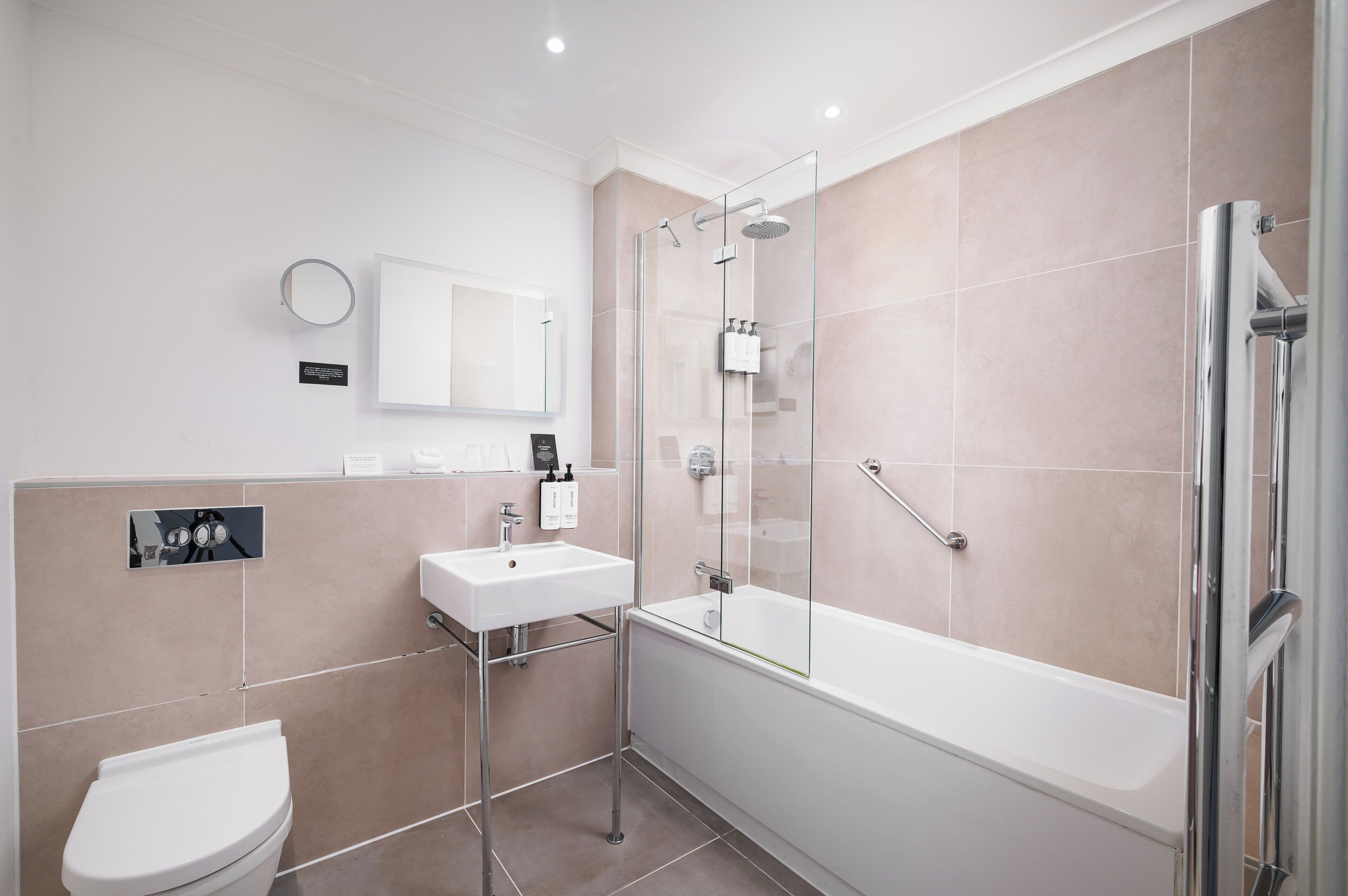 A modern bathroom with a glass-enclosed shower, a white sink, and a toilet.