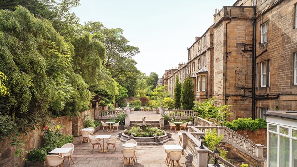A courtyard with outdoor seating, a central fountain, and stone buildings. - voco Edinburgh - Royal Terrace by IHG (Edinburgh)