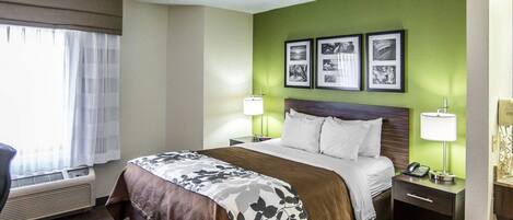 Habitación de hotel con cama, mesitas de noche, lámpara, teléfono y cuadros en la pared.
