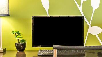 Un escritorio con un monitor de computadora, teclado y una pequeña planta en maceta.