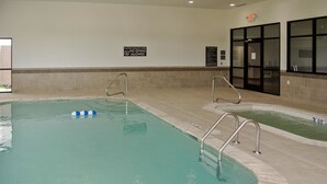 An indoor swimming pool with clear water, two ladders, and a no diving sign.