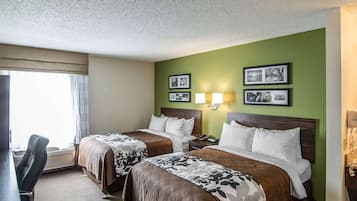 A hotel room with two beds, a desk, and a chair. There are wall-mounted lamps and framed pictures.