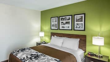 A hotel room with a bed, two bedside tables, a nightstand, a lamp, and three framed pictures on the wall.
