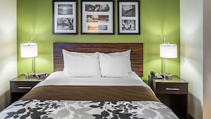 A hotel room with a large bed, two bedside tables with lamps, a wooden headboard, and three framed pictures on the wall.