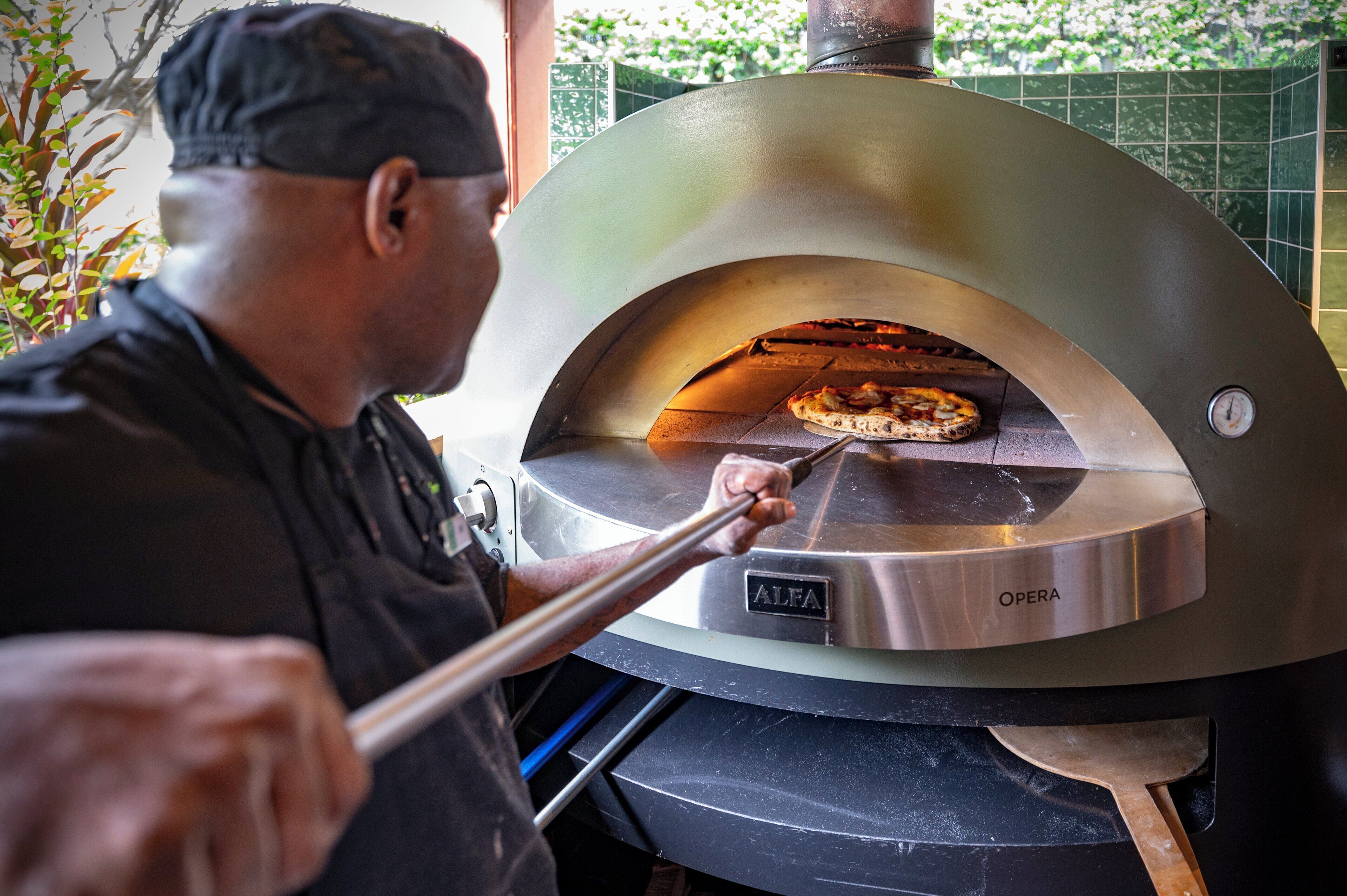 A person using a pizza oven with a digital display, likely for temperature control.