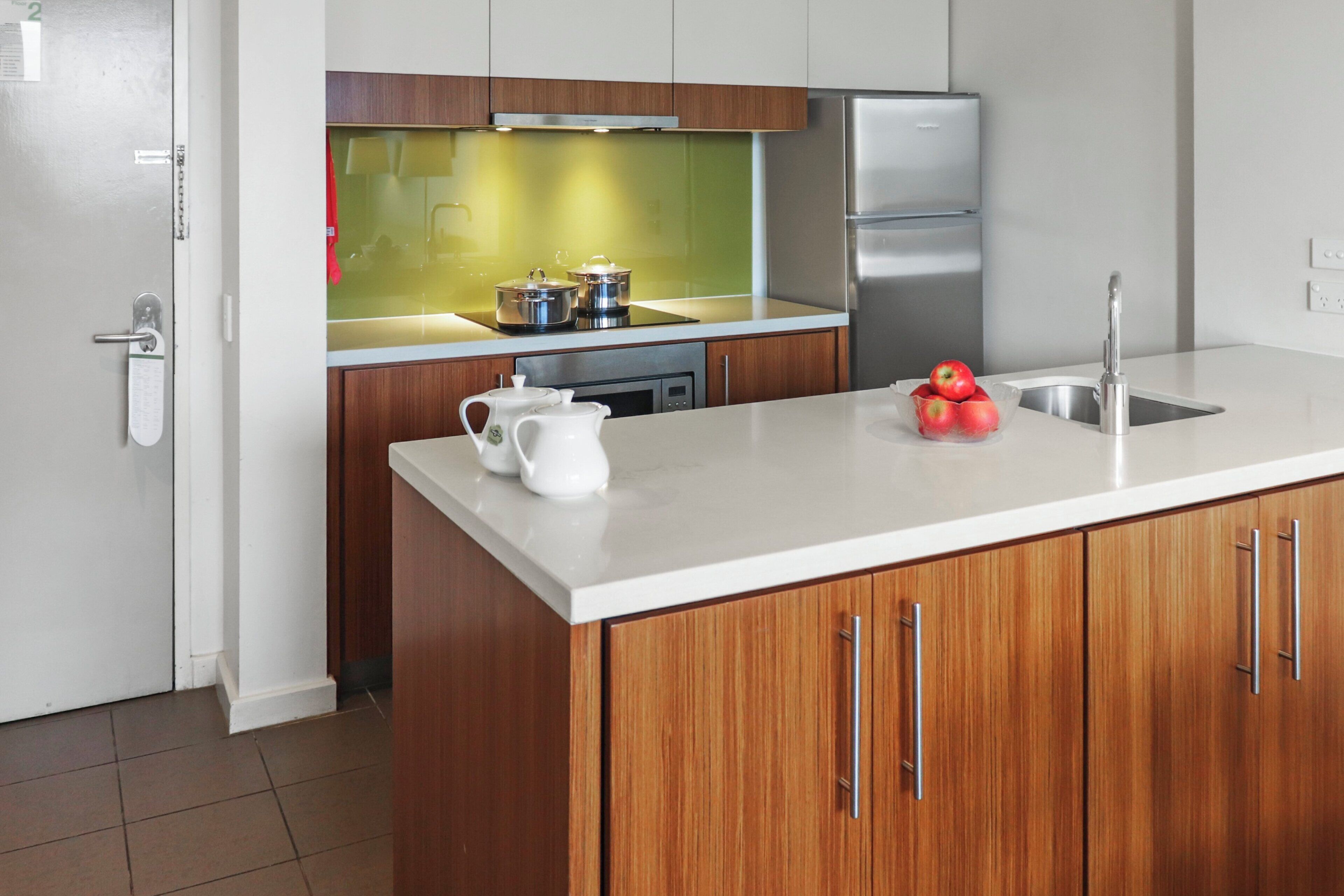 A modern kitchen with wooden cabinets, stainless steel appliances, and a white countertop.