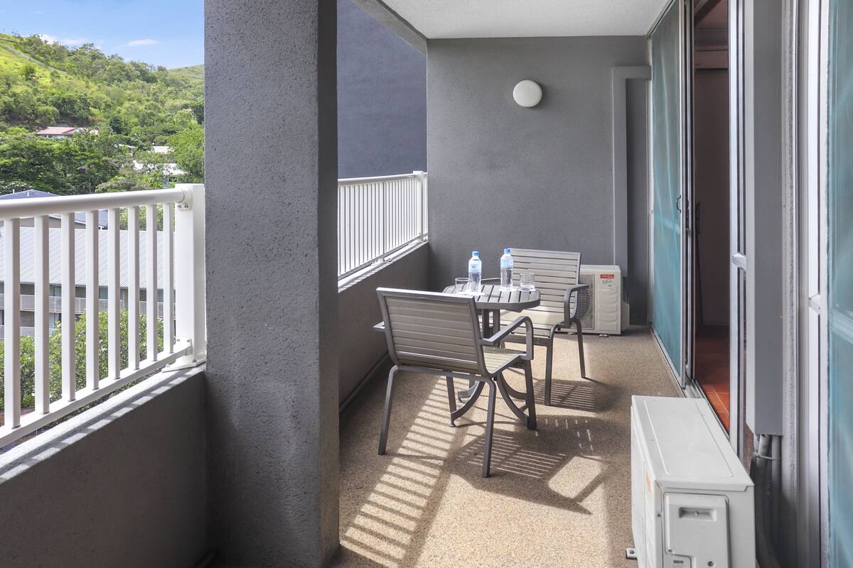 A balcony with a table and chairs, a water dispenser, and a heater.