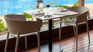 A dining area with a view of a swimming pool, wooden flooring, and a ceiling fan. - Holiday Inn Port Moresby by IHG (Port Moresby)