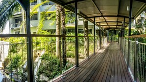 A covered wooden walkway with metal railings, surrounded by lush greenery and a building in the background. - Holiday Inn Port Moresby by IHG (Port Moresby)