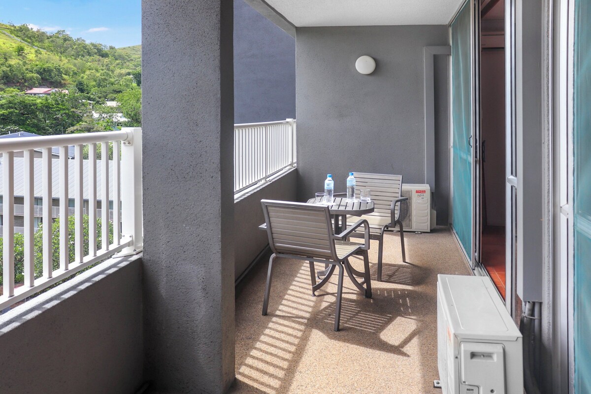 A balcony with a table and chairs, a water dispenser, and a heater.