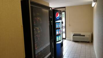 Máquina expendedora con el logo de Pepsi, un refrigerador y un aire acondicionado montado en la pared en un pasillo.