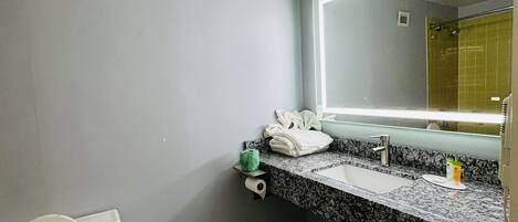 A bathroom with a toilet, sink, and mirror.