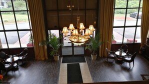 A lobby with a chandelier, potted plants, and seating areas.