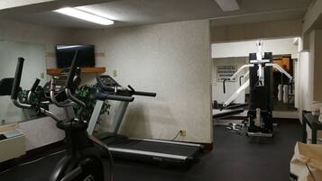 A gym with a treadmill, elliptical, and weight machines.