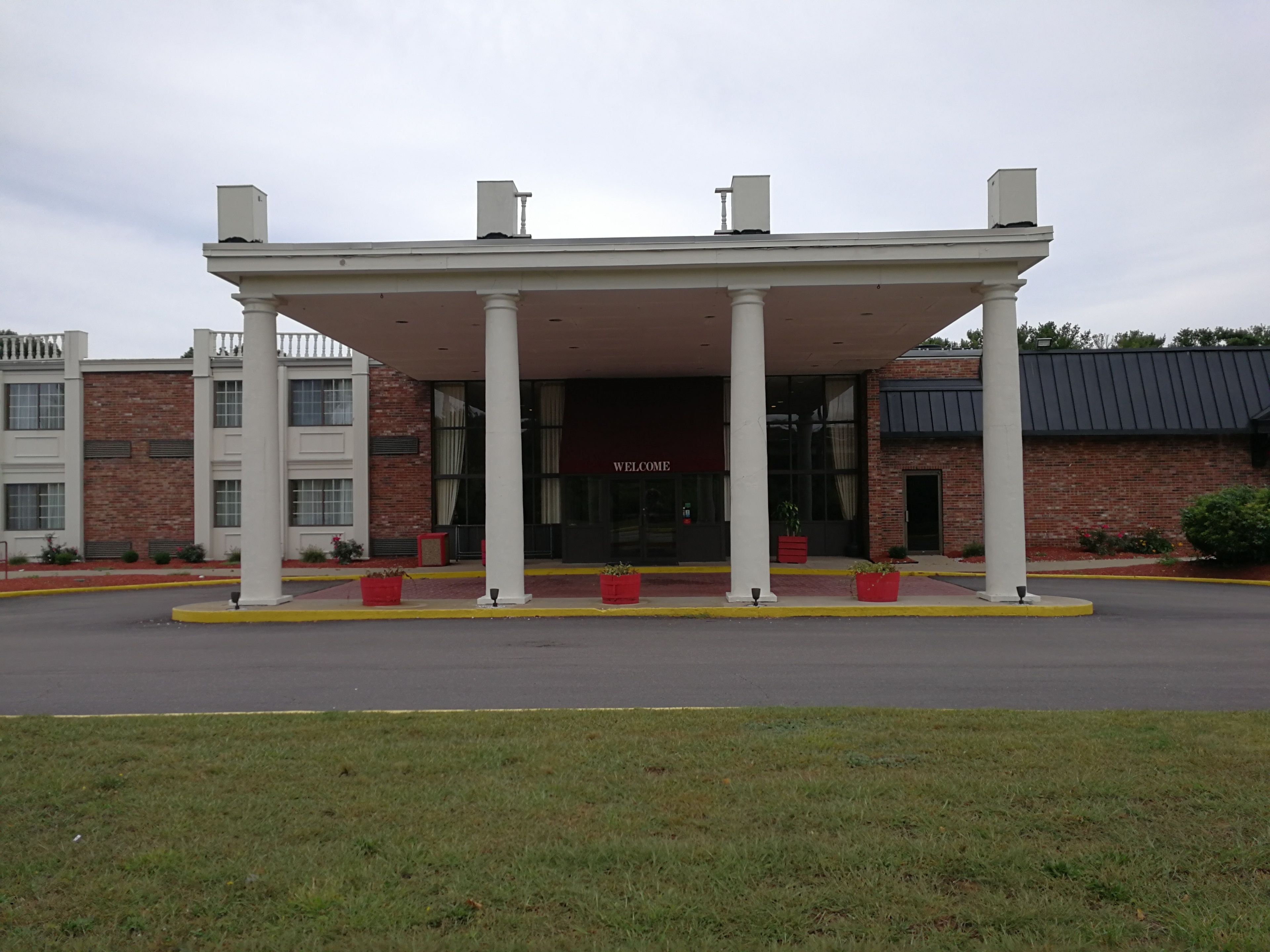 A building with a covered entrance, columns, and a brick facade.