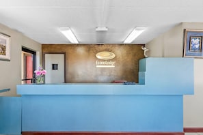 A reception desk with a logo, a framed picture, and a vase with flowers.