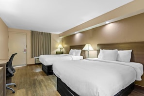 A hotel room with two beds, a desk, and a chair.