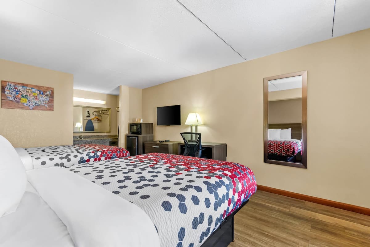 Una habitación de hotel con una cama grande, un escritorio, una silla, un televisor y un espejo.