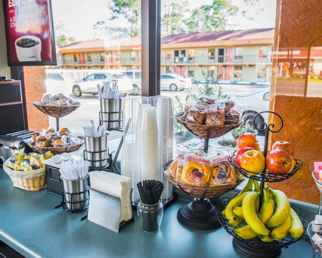 A buffet setup with various food items, utensils, and a window view of a parking area.