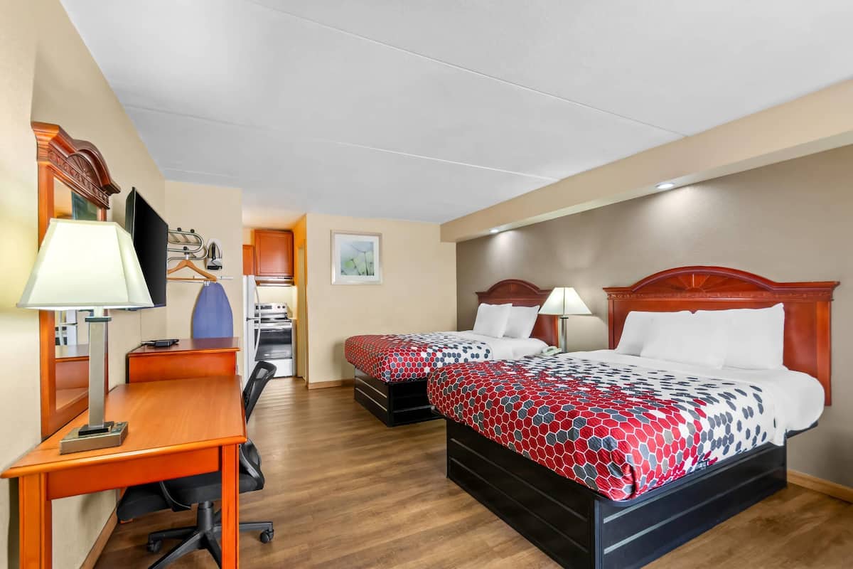 Habitación de hotel con dos camas, un escritorio, una silla, un televisor y un baño.