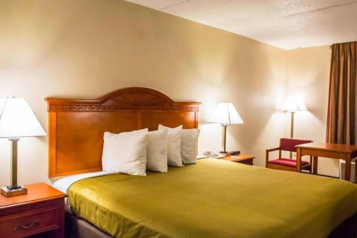 Una habitación de hotel con cama, dos lámparas de noche, un escritorio y una silla.