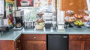 Una barra de desayuno con cafetera, tostadora y diversos alimentos.