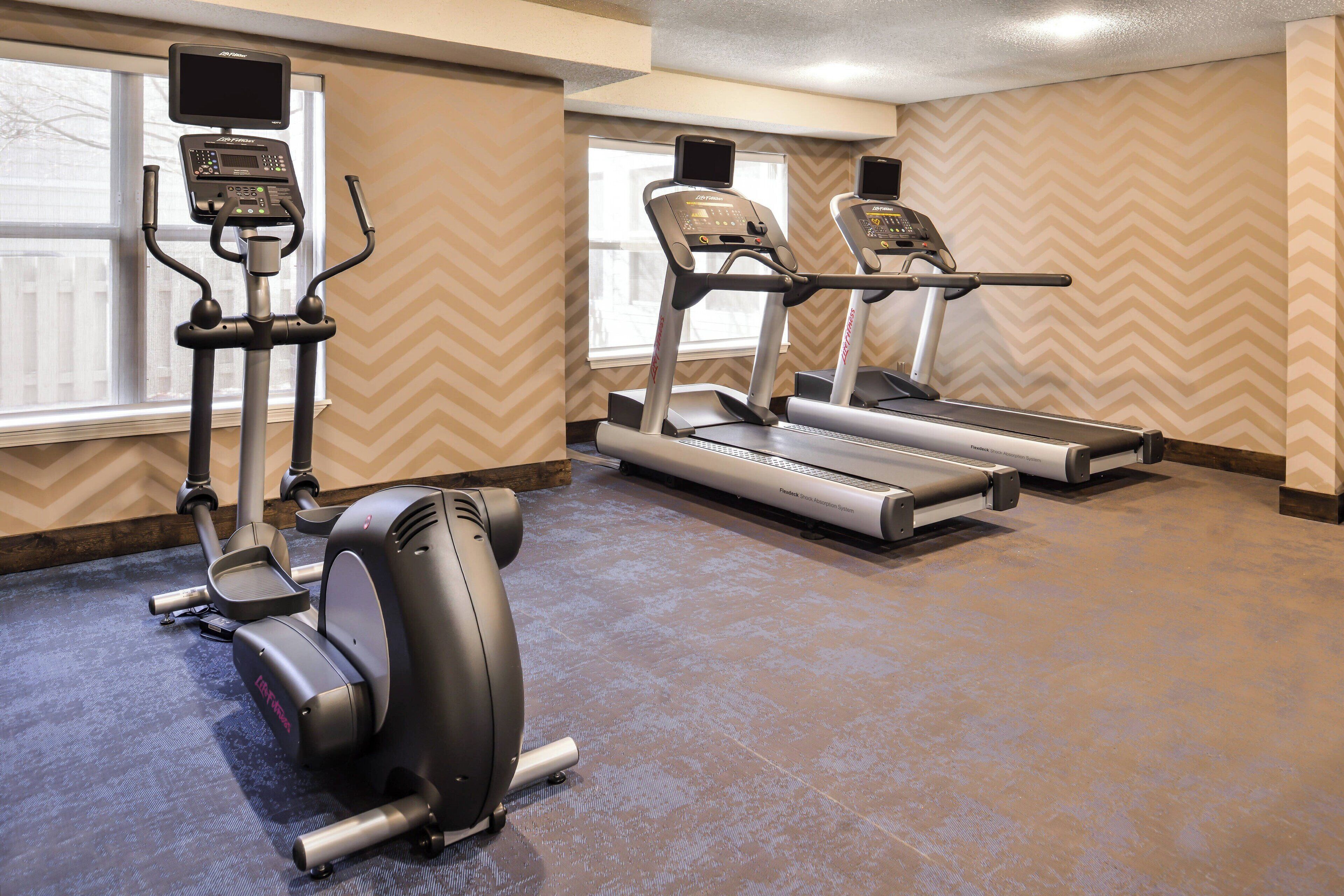 Une salle de sport équipée d'un vélo elliptique, d'un vélo d'appartement et de tapis de course.