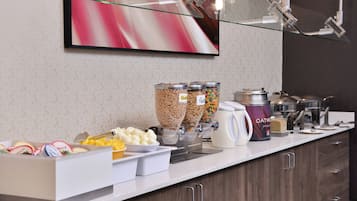 A breakfast buffet setup with various food items and containers.