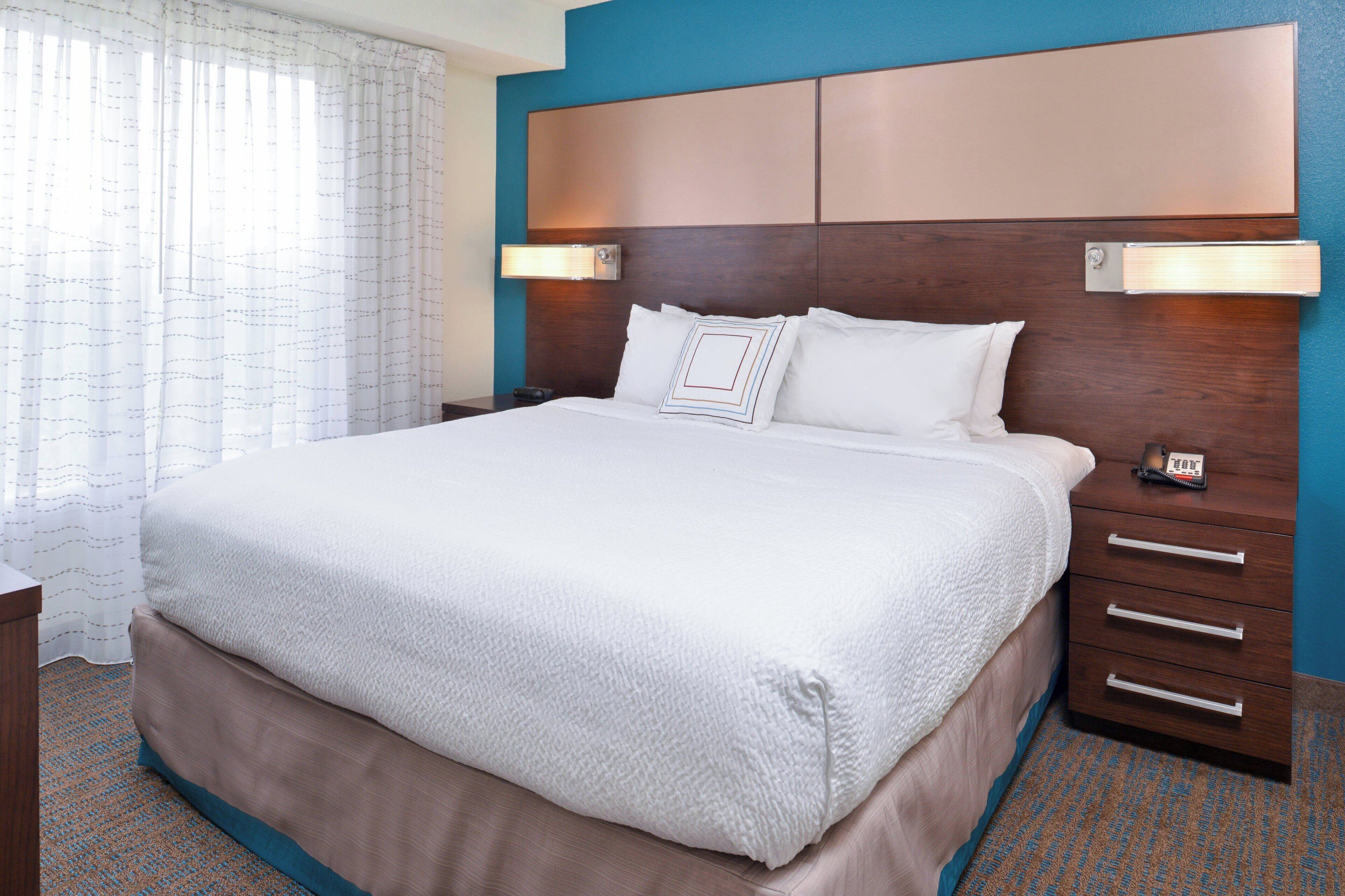 A hotel room with a large bed, a wooden headboard, bedside lamps, and a nightstand.