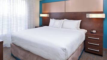 A hotel room with a large bed, a wooden headboard, bedside lamps, and a nightstand.