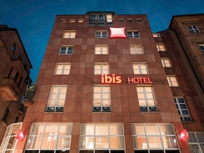 Un edificio de hotel con un llamativo letrero de 'ibis' y la palabra 'HOTEL' en la fachada.