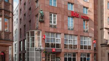 Ein Hotel mit rotem Schild, großen Fenstern und einer Statue an der Ecke.