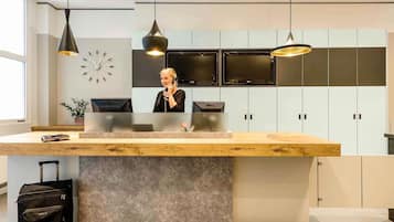 A reception desk with a modern design, a clock on the wall, and a large window providing natural light.