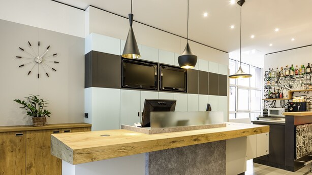 A modern kitchen with a wooden island, black cabinets, and pendant lighting. - ibis Nuernberg Altstadt (Nuremberg)