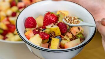 A bowl of fruit salad with a spoonful of granola.