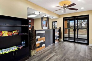 A hotel lobby with a reception desk, shelves with snacks, a ceiling fan, and a view through the glass doors. - Best Western Greenville Inn (Greenville)