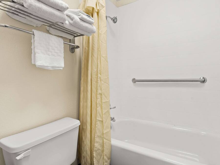 A bathroom with a toilet, a bathtub, a shower, and a towel rack with folded towels.