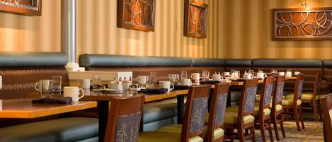 A restaurant with booths and high-top tables, featuring striped wallpaper and decorative wall art.
