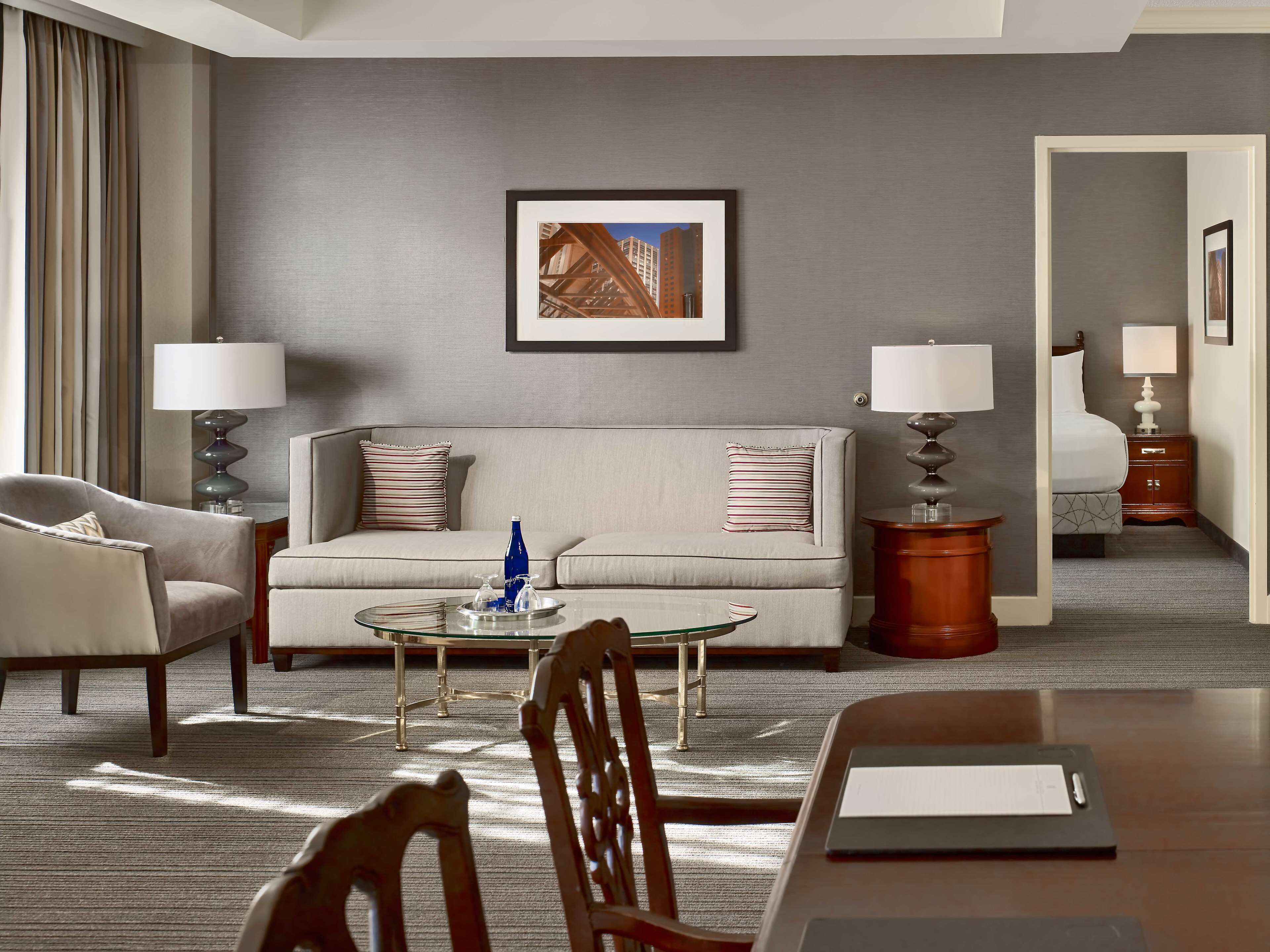 A hotel room with a sofa, armchairs, a coffee table, a desk, and a bed.