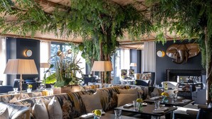 A restaurant with indoor plants, a sofa, dining tables, and a fireplace.