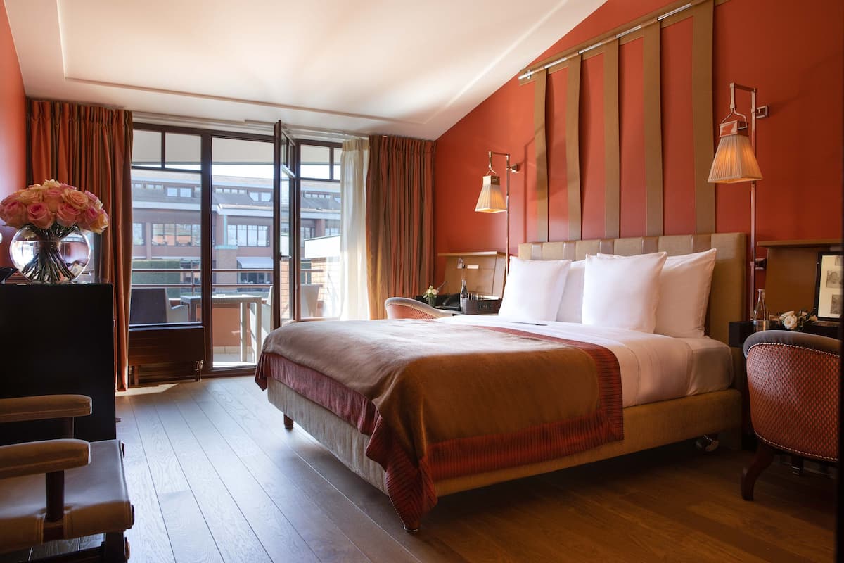 A hotel room with a large bed, a desk, a chair, and a view of the outside.