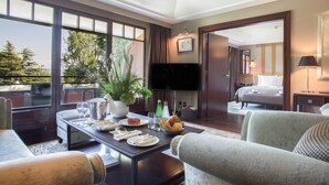 A hotel room with a dining area, a TV, a bed, and a view of the outdoors.