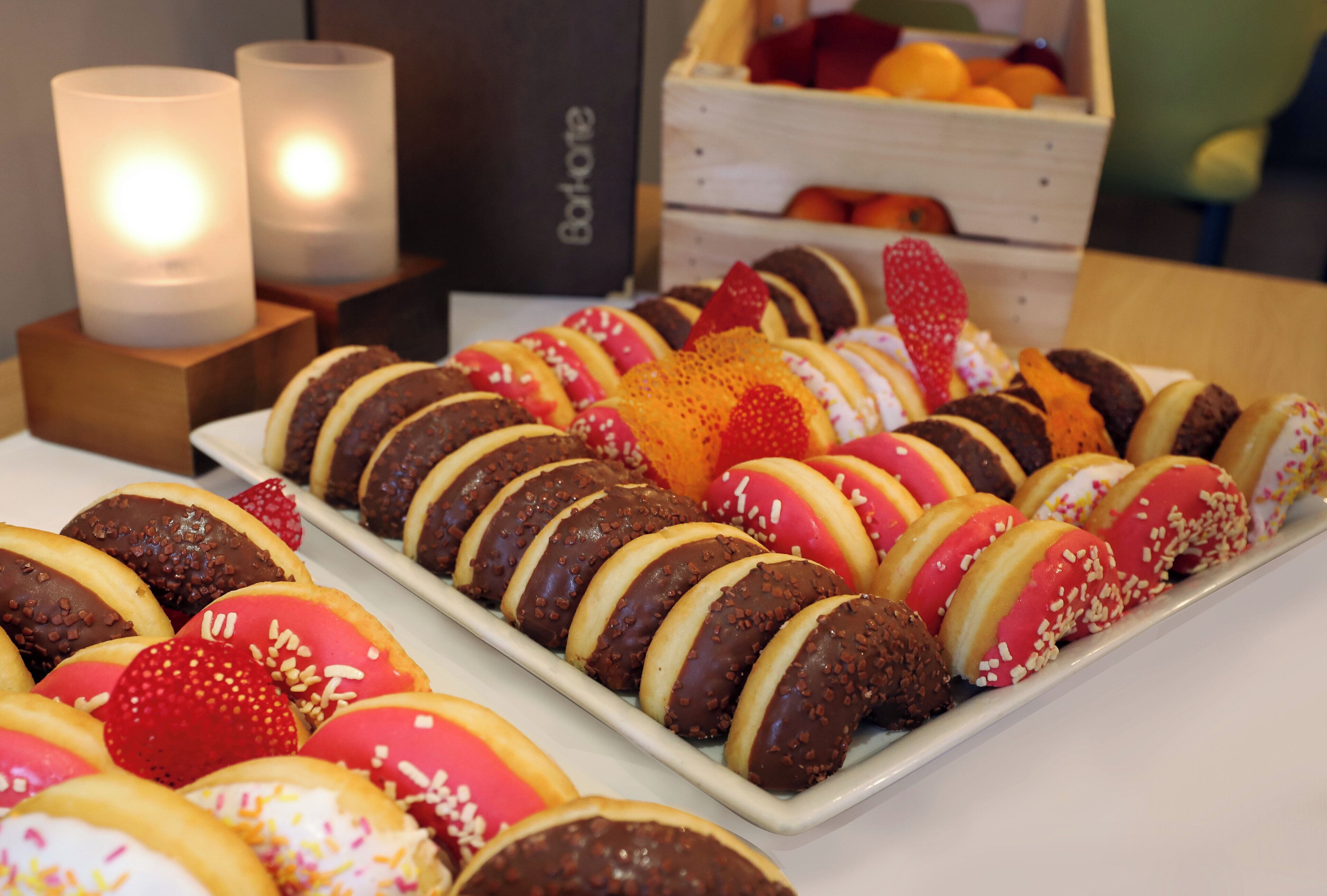A tray of assorted donuts with various toppings and a candle in the background.