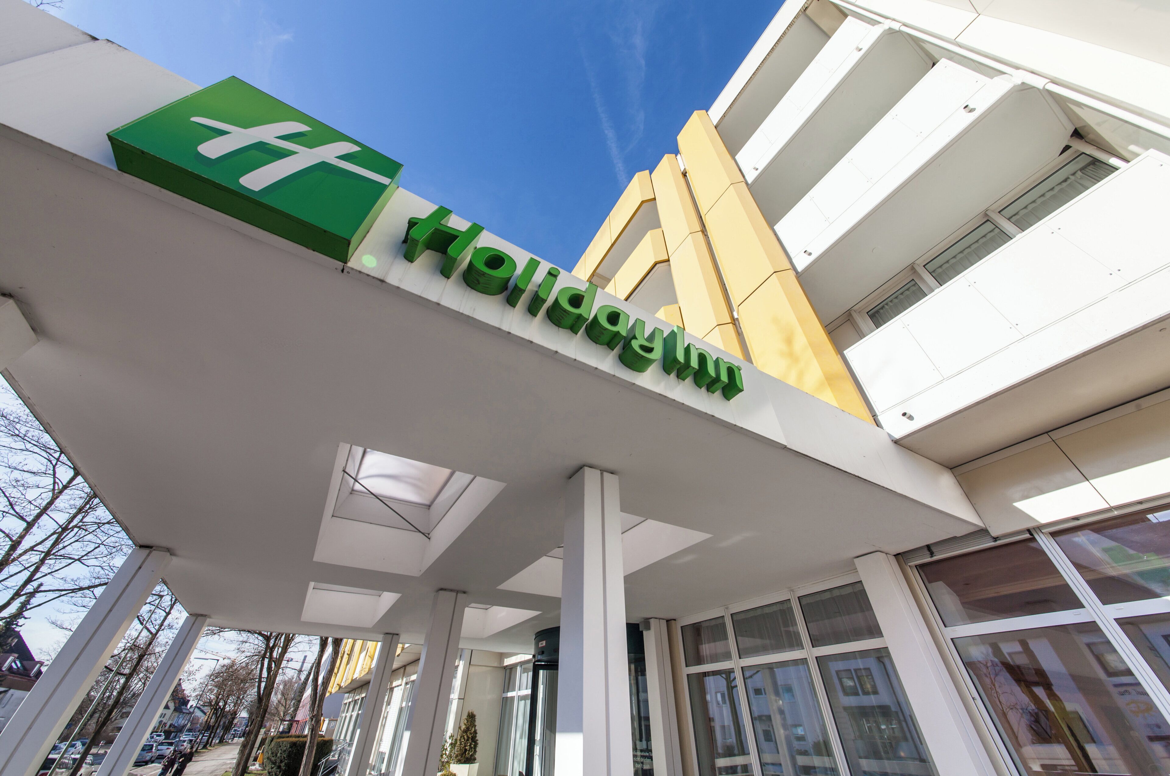 A hotel sign with the name 'Holliday Inn' in green letters on a white background.