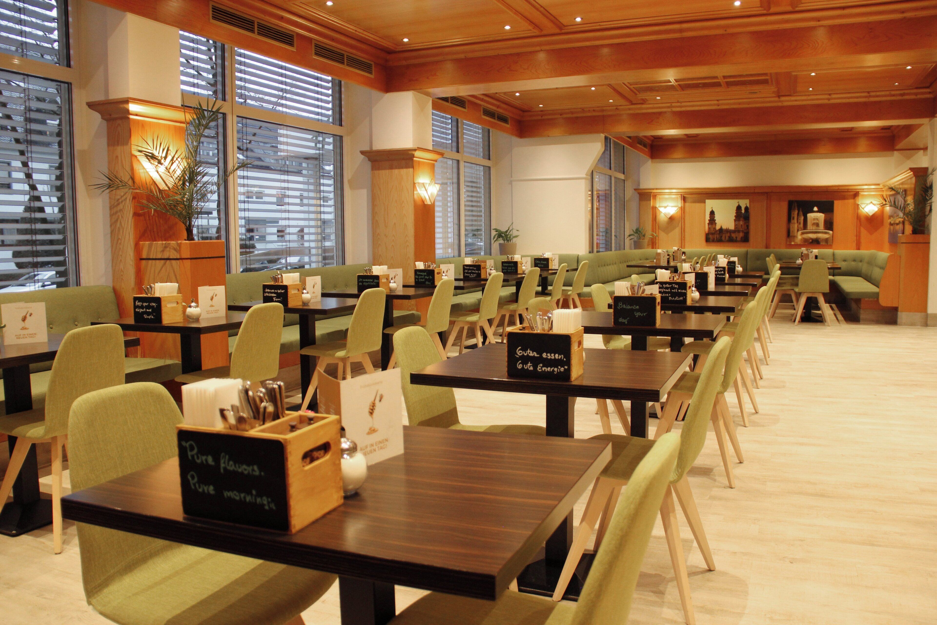 Un ristorante con diversi tavoli e sedie, ampie finestre e un ambiente accogliente.