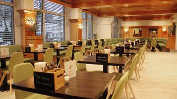 Un ristorante con diversi tavoli e sedie, ampie finestre e un ambiente accogliente.