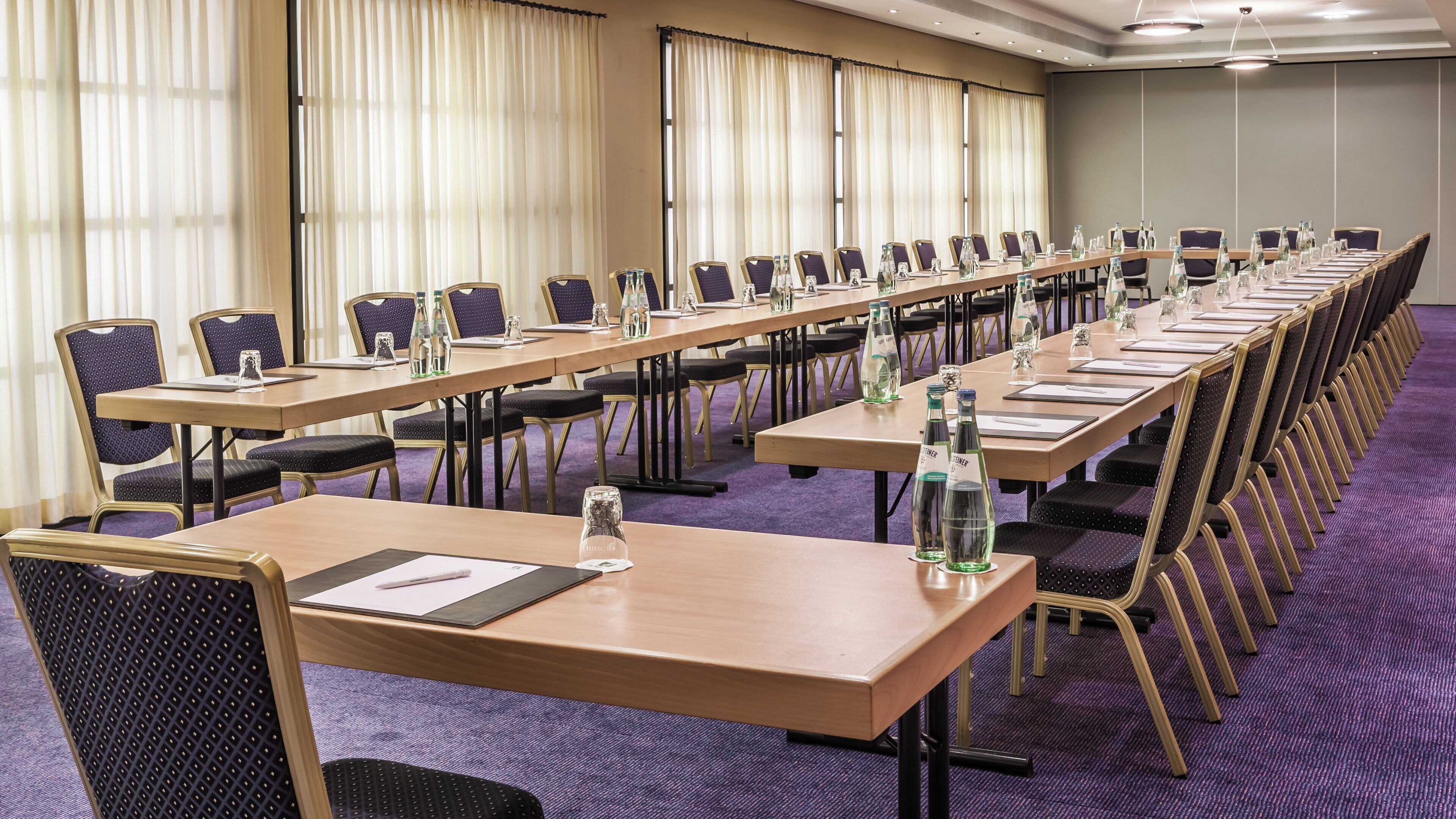 A conference room with long tables, chairs, and water bottles.