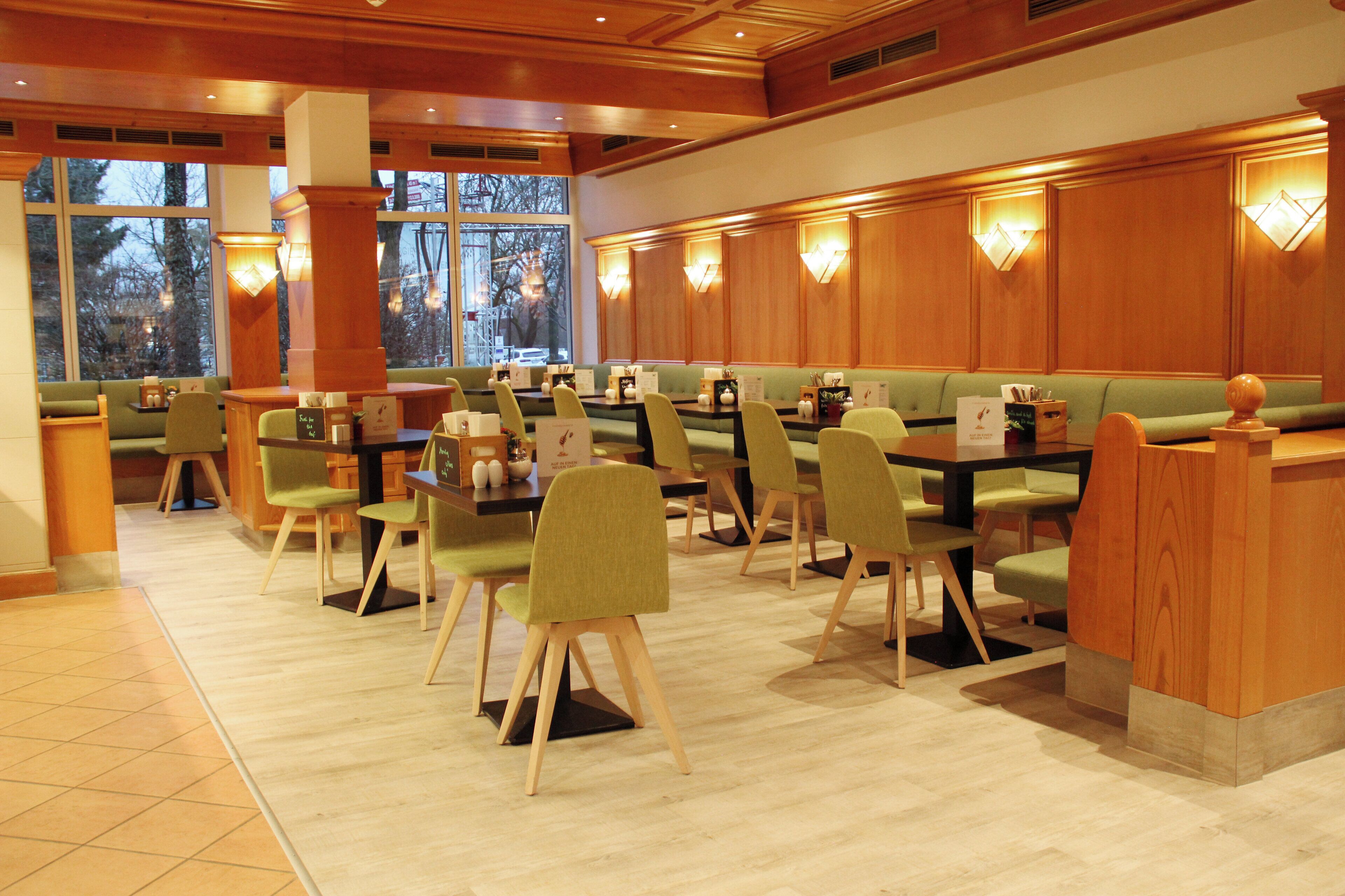 Un restaurante con asientos y mesas de madera, y luces fijadas a la pared.