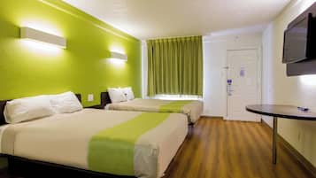 A hotel room with two beds, a television, a door, and a small table.